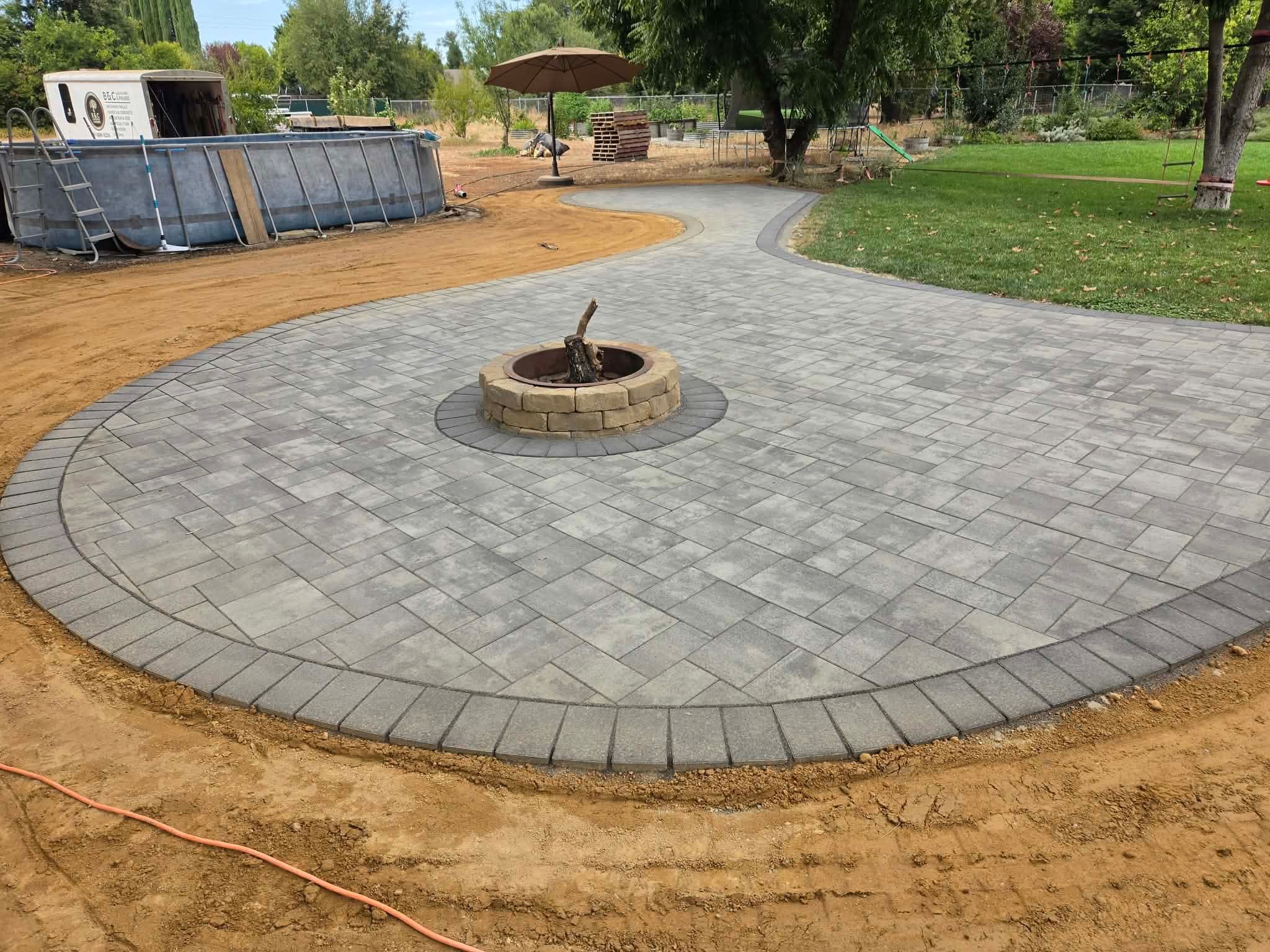 Wide view of a Premier Smooth Torino paver patio surrounding a circular fire pit