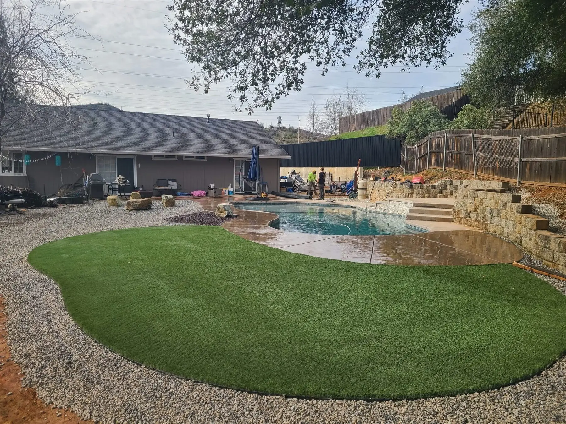Curved backyard artificial turf lawn beside a swimming pool